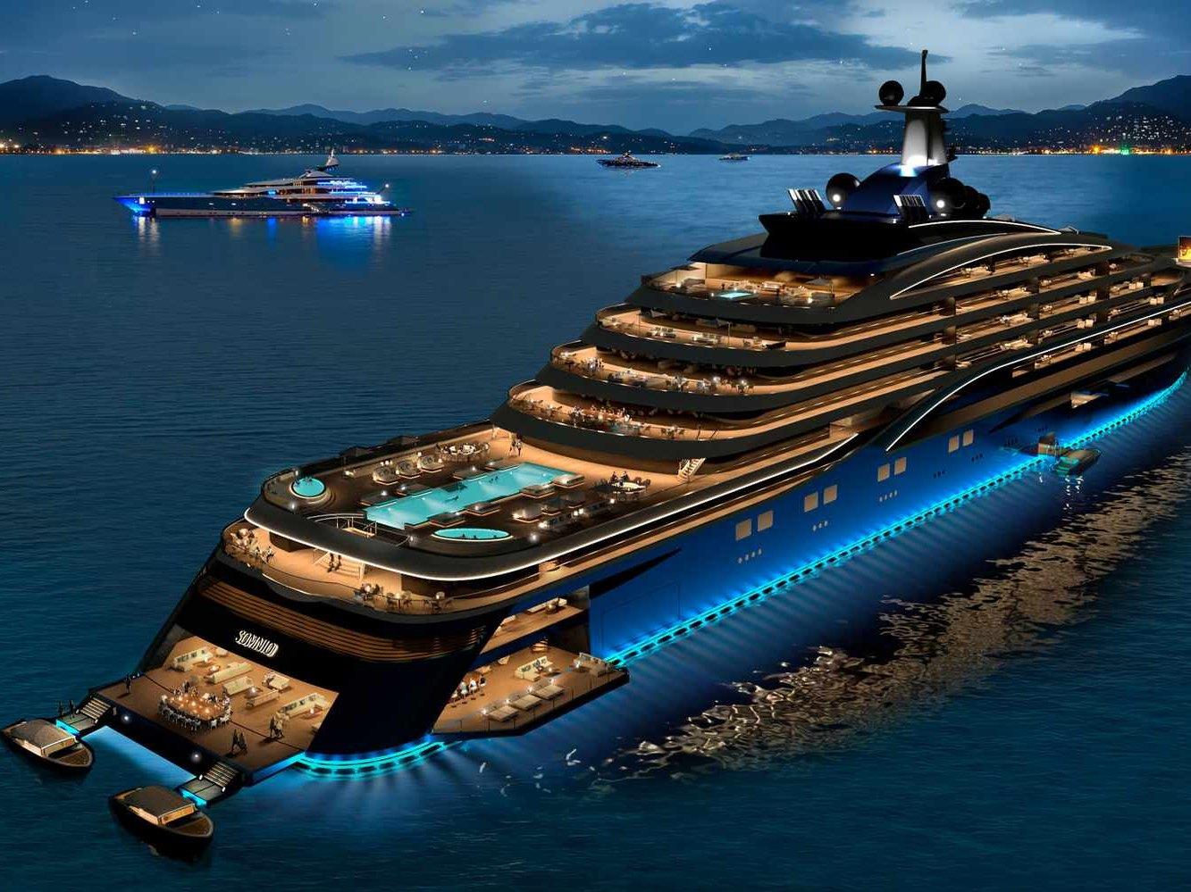 A large superyacht lit at night at anchor off a coastline