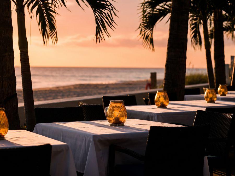 A palm-lined restaurant terrace at dusk