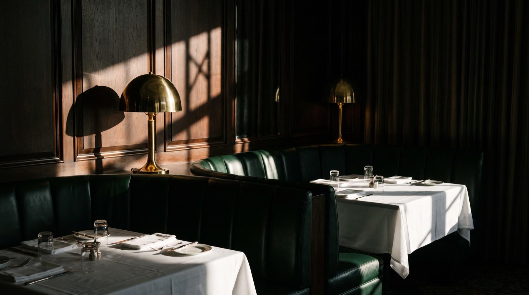 A classic continental dining room with green banquettes and brass lamps